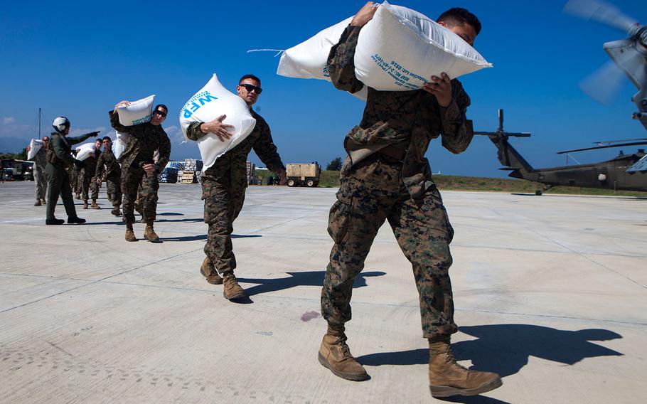 U.S. Marines and sailors load relief supplies onto helicopters at Port-au-Prince, Haiti on Oct. 13, 2016