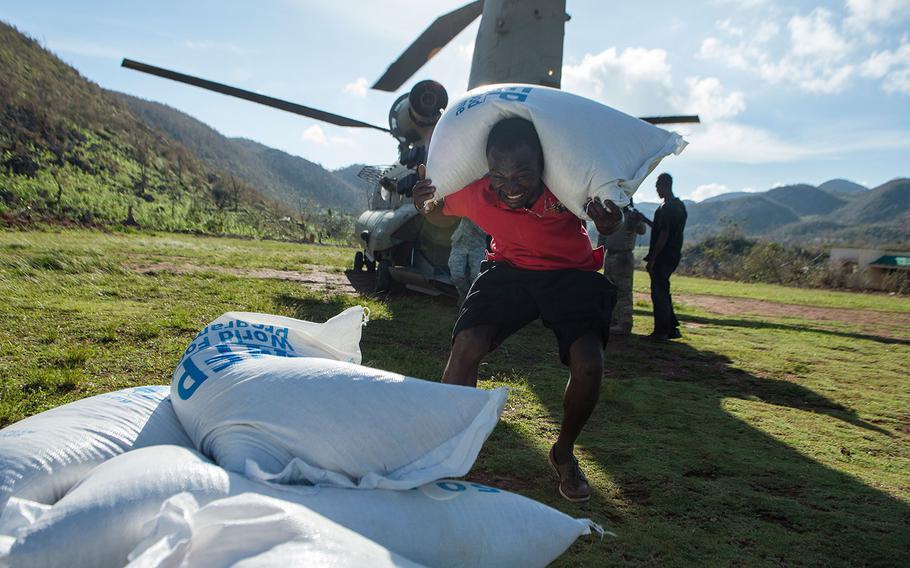 A citizen of Beaumont, Haiti unloads a bag of rice from a CH-47 Chinook helicopter on Oct. 13, 2016.