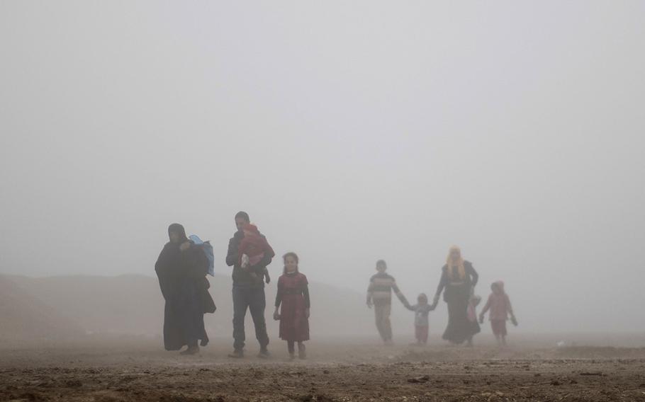 In this Friday, March 17, 2017 file photo, displaced people walk through heavy fog during fighting between Iraqi security forces and Islamic State militants in west Mosul, Iraq.