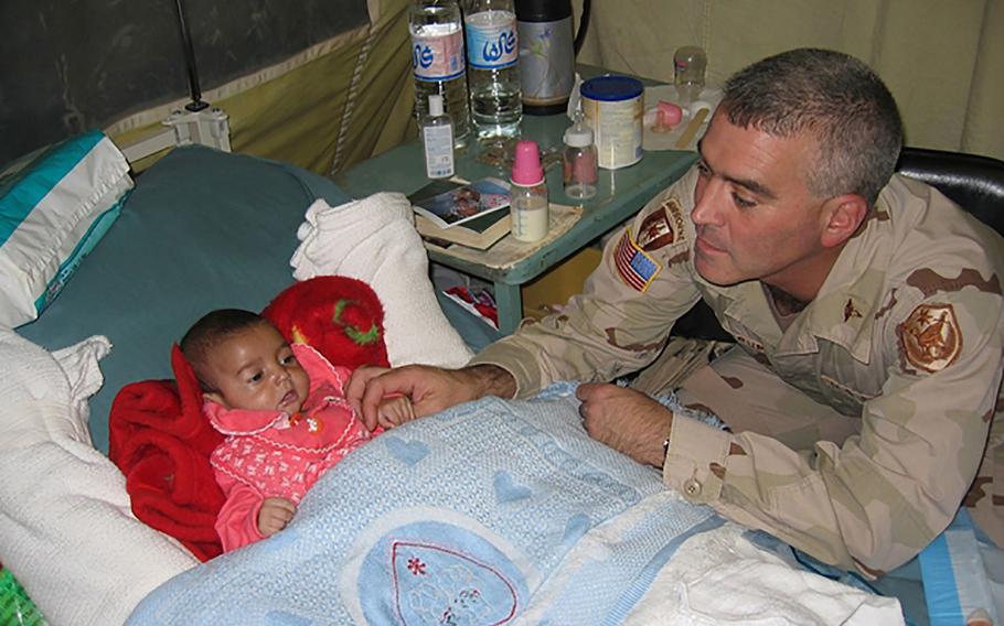 Maj. Brad Wenstrup, chief of surgery at the Abu Ghraib Hospital, plays with Tabark Addul Rahman, aka Baby Tabitha on Oct. 30, 2005.
