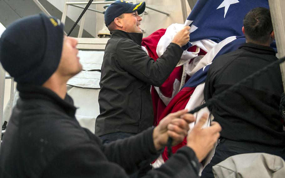 Cmdr. Bryce Benson, commanding officer of the destroyer USS Fitzgerald, brings down the ensign while serving aboard the ship in the Pacific Ocean as executive officer in February 2016. 