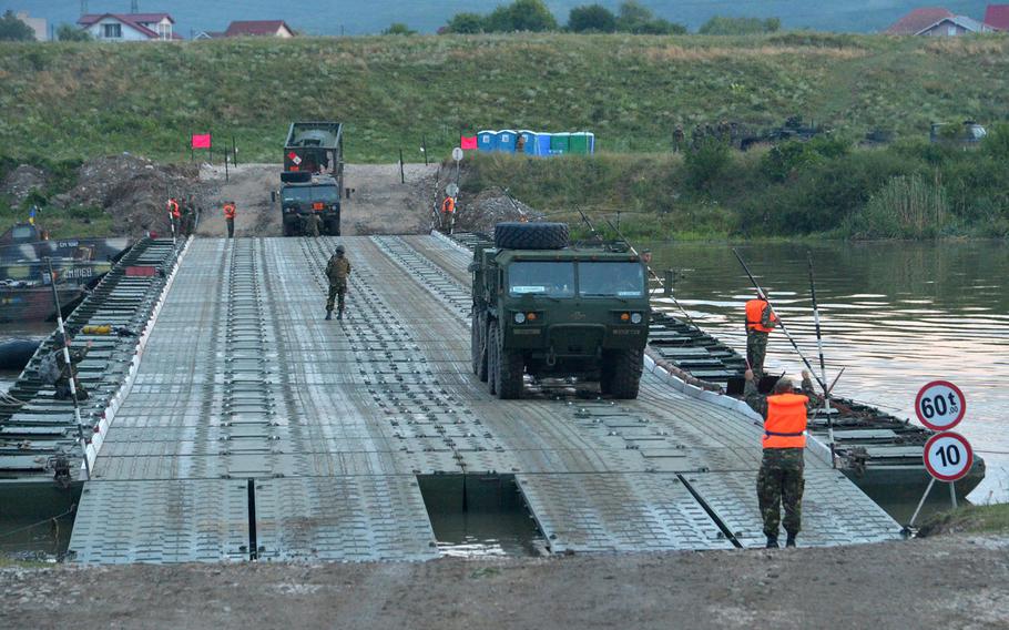 Trucks of the U.S. Army's 2nd Cavalry Regiment cross a Romanian bridge across the Olt River near Ramnicu Valcea, Romania, early Monday, July 17, 2017 during a night river crossing operation.