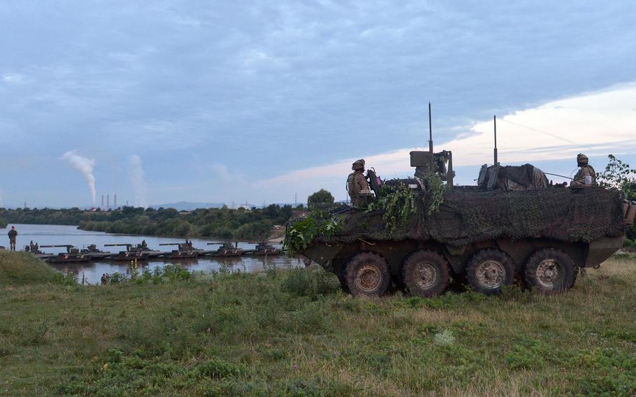 Sitting in their Stryke, soldiers of the 2nd Cavalry Regiment watch their unit cross the Olt River near Ramnicu Valcea, Romania, early Monday, July 17, 2017 during a  river crossing operation. In the background is the bridge a German unit constructed on the river during the night.
