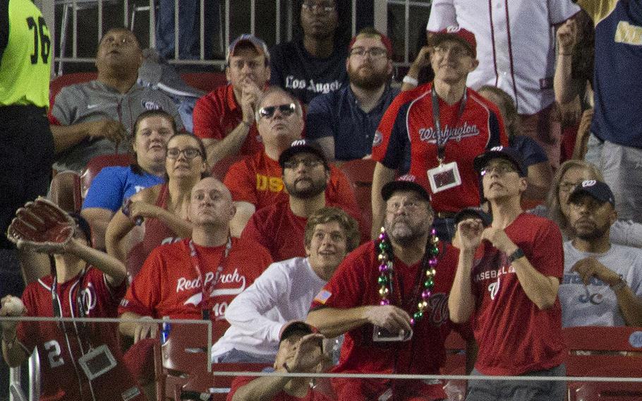 Fans in the bleachers follow the path of an approaching baseball hit by Milwaukee's Travis Shaw for a three-run homer during a game between the Washington Nationals and the Brewers at Nationals Park in Washington, D.C., July 25, 2017.
