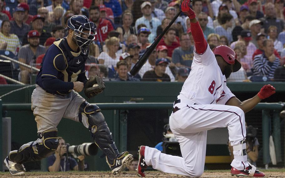 Washington Nationals batter Brian Goodwin goes down on strikes, literally, as Milwaukee Brewers catcher Manny Pina moves in to make the tag during a game at Nationals Park in Washington, D.C., July 25, 2017.
