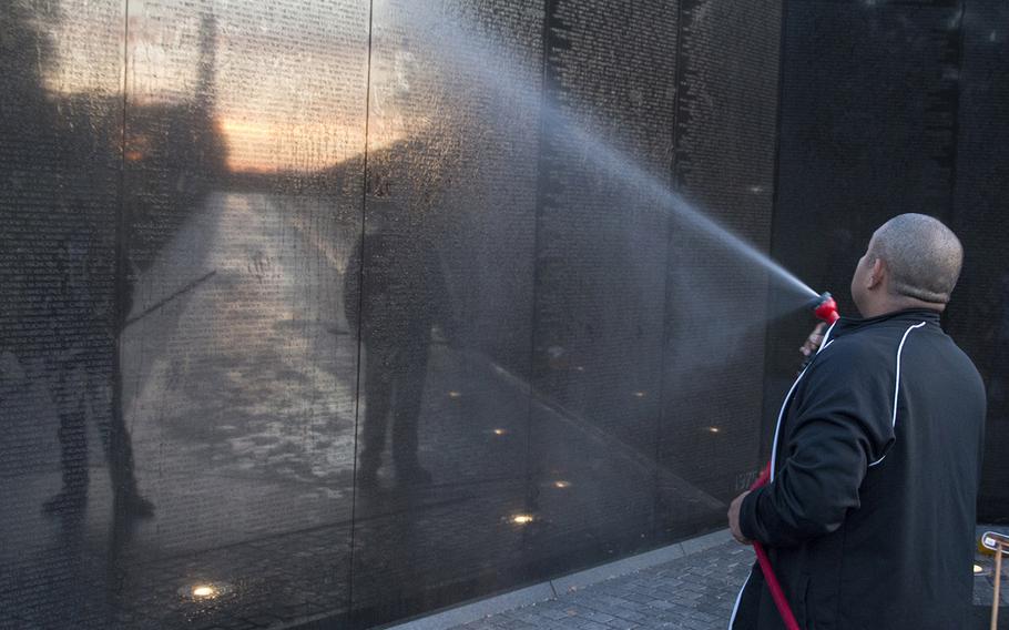 The Washington Monument and the rising sun are reflected in the Vietnam  Veterans Memorial as a volunteer from Dover Air Force Base, Del., washes the Wall in Washington, D.C., on Oct. 22, 2017.