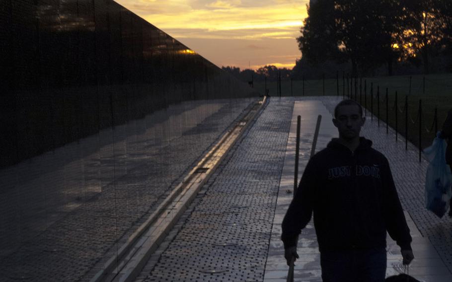 An airman from Dover Air Force Base, Del., in Washington, D.C. to help clean the Vietnam Veterans Memorial, is silhouetted against the rising sun on Oct. 22, 2017.