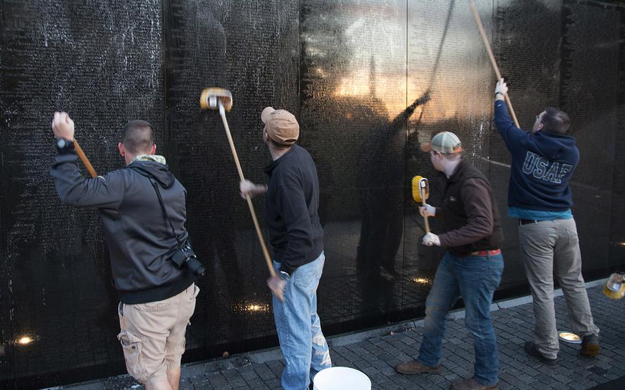 The Washington Monument and the rising sun are reflected in the Vietnam Veterans Memorial as airmen from Dover Air Force Base, Del., use soft brushes and mild detergent to clean the Wall at sunrise on Oct. 22, 2017.
