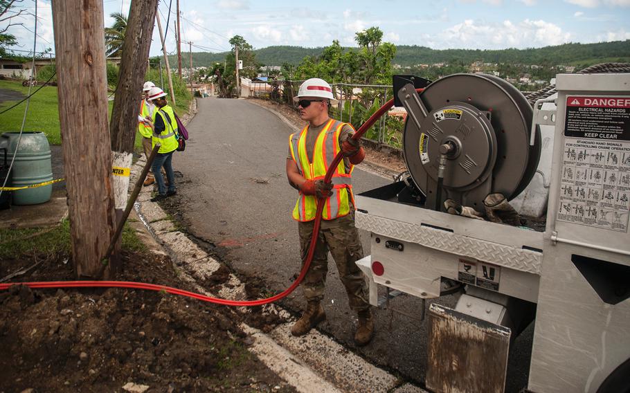 Pfc. Matheau Sicard, a member ot the 249th Engineer Battalion, feeds a line to fellow workers about to use a hydraulic tamper at a work site in a neighborhood near San Juan, Puerto Rico, on Nov. 10, 2017, nearly eight weeks after Hurricane Maria caused substantial damage across the island.