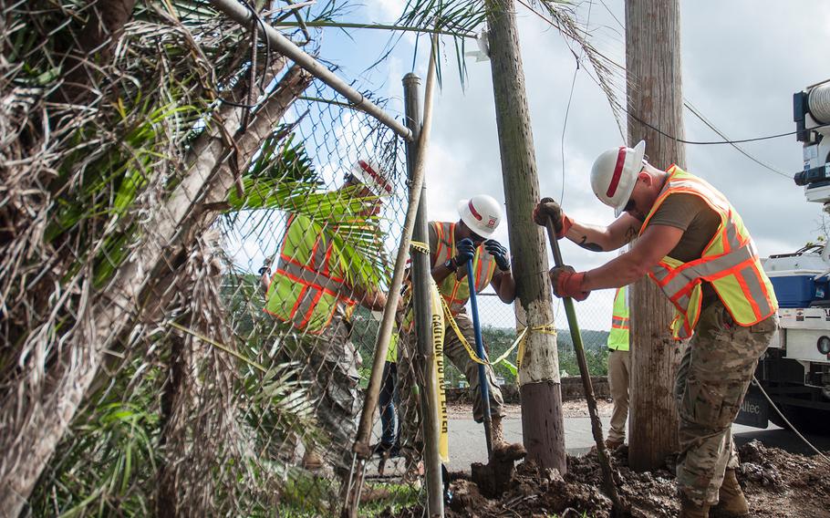 Soldiers with the 249th Engineer Battalion shovel debris out of an area where they were planning to tie a guy wire from a utility pole to a ground anchor to keep the pole upright in a neighborhood near San Juan, Puerto Rico, on Nov. 10, 2017.