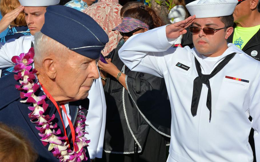 A sailor honors a World War II veteran departing a ceremony commemorating the 76th anniversary of the surprise attack on Pearl Harbor in Honolulu, Thursday, Dec. 7, 2017.