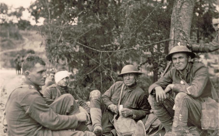 Allied soldiers, one with a bandaged head, sitting on the ground during World War I. 