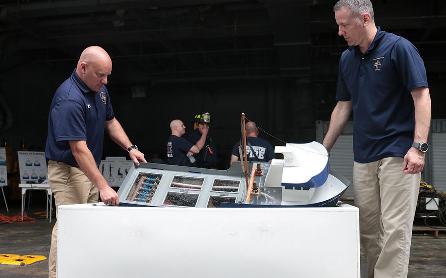 Coast Guard Chief Warrant Officers Rob Birdwell, left, and David Porco, came to Norfolk, Va., from their training center in Coast Guard Training Center Yorktown, Va., to teach firefighters about the unique challenges of keeping a ship afloat while fighting a massive fire on it. Here, they demonstrate that on a model at the 27th annual Marine Firefighting School held May 14-19 in Norfolk. 