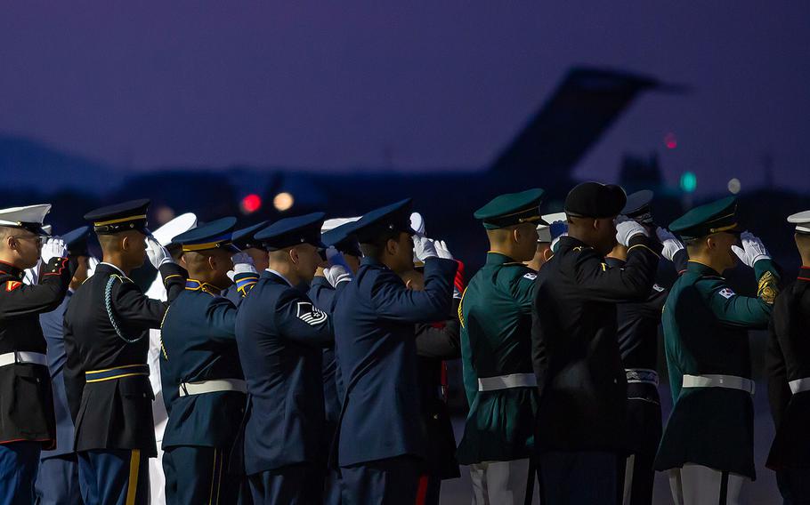 A multinational honor guard salutes an Air Force transport plane as it attempts to take off from Osan Air Base, South Korea to Hawaii, Wednesday, Aug. 1, 2018.