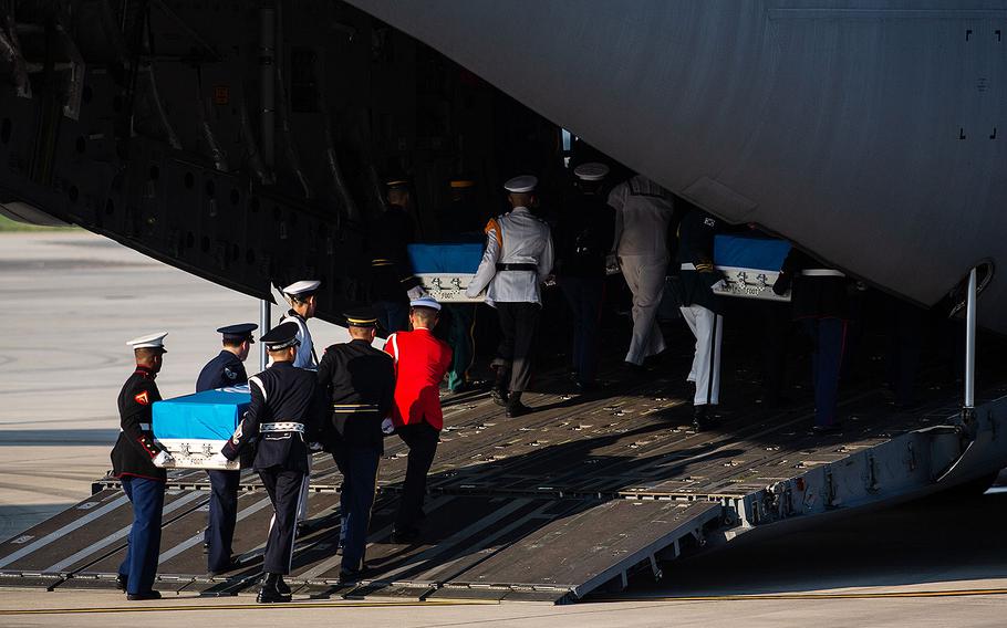 A multinational honor guard loads three caskets onto an Air Force transport plane at Osan Air Base, South Korea for their trip to Hawaii on Wednesday, Aug. 1, 2018.
