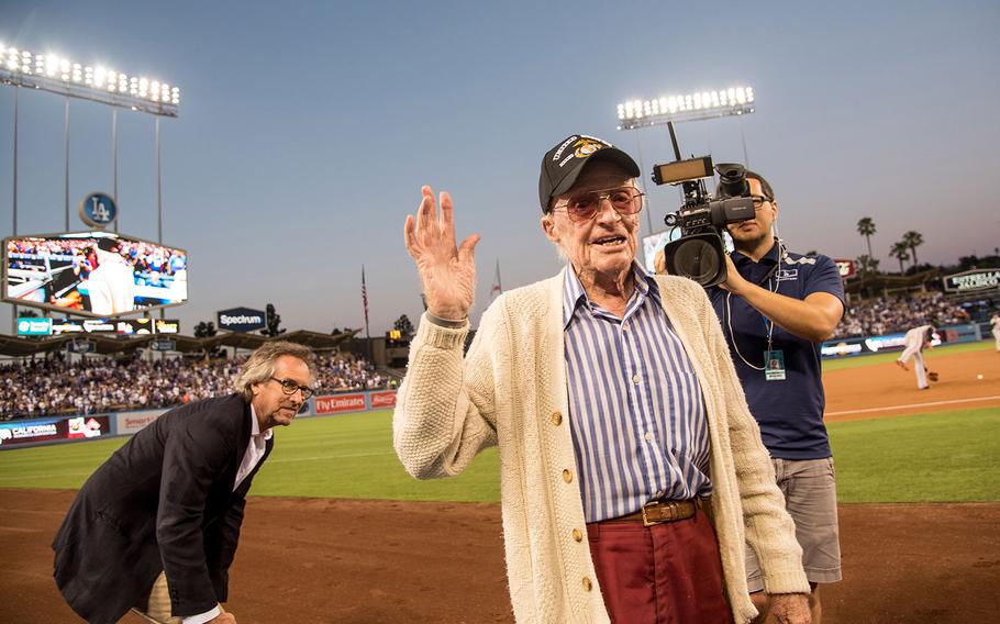 Marine veteran Sam Folsom, 98, a fighter pilot who shot down three Japanese planes during the Battle of Guadalcanal in World War II, later served in the Korean War and retired as lieutenant colonel waves to the crowd at Dodger Stadium in Los Angeles on Aug. 14, 2018 as his son, Gerrit Folsom, left, looks on. The Dodgers honored Folsom, who lives in nearby Santa Monica, Calif., as their Hero of the Game.