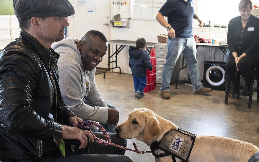 Actor Warren Christie, left, and military consultant Jamel Daniels, right, part of the cast of the new TV show "The Village," visit Warrior Canine Connection in Boyds, Maryland, on November 10, 2018, to learn about service dogs and their role helping veterans. The show will air in 2019. 