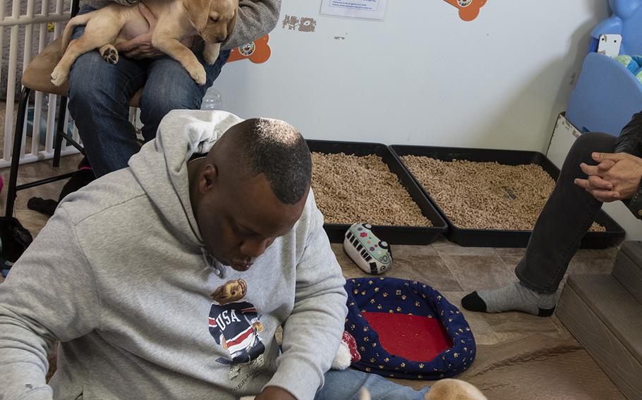Military consultant Jamel Daniels, foreground, part of the cast of the new TV show "The Village," visits Warrior Canine Connection in Boyds, Maryland, on November 10, 2018, to learn about service dogs and their role helping veterans. The show will air in 2019. Seated is actor Dominic Chianese, known for his roles in "Sopranos" and "The Godfather Part II."