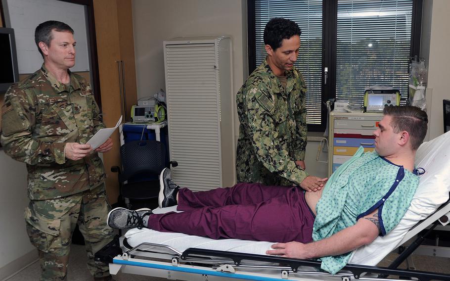U.S. Air Force Maj. Mark Lytle, vascular surgeon at Eglin Air Force Base's 96th Medical Group, observes orthopedic surgeon Lt. Andrew Wright's examination of Petty Officer 3rd Class Kyle Benson during simulation at Naval Hospital Pensacola on Jan. 31, 2019. 