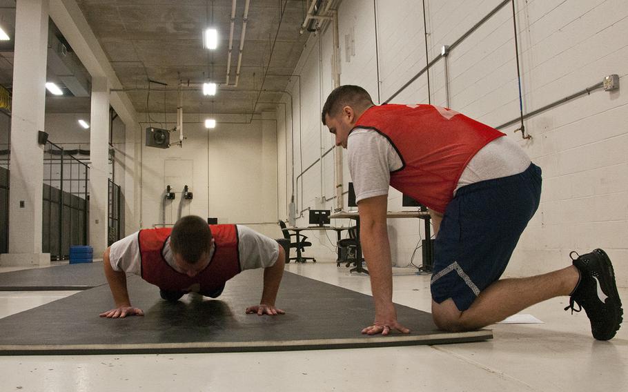 U.S. Air National Guard Staff Sgt. Jaron Ross counts push-ups for U.S. Air National Guard Staff Sgt. Michael J. Walker, both base services specialists with the 121st Air Refueling Wing, on April 6, 2018, in Hangar 885 at Rickenbacker Air National Guard Base, Ohio. 