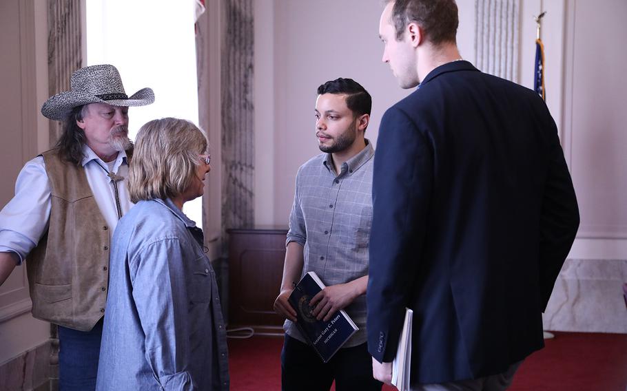 Donna Ellis Cornell, daughter of Sgt. 1st Class Melvin Hatt, speaks to two senate aides March 15, 2019, at the Russell Senate Building while her husband, Robert Cornell, far left, looks on. 