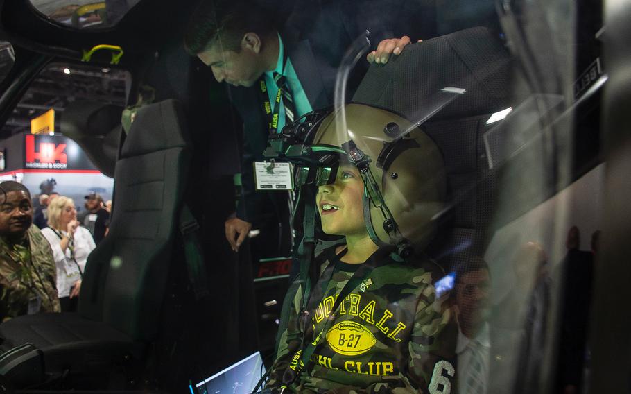 Konrad Kreis, 9, from Pensacola, Fla., looks through the eyepiece of a smart helmet as he sits in the cockpit of a Bell V-280 Valor tilt rotor aircraft on display at the 2019 AUSA convention in Washington, D.C., on Tuesday, Oct. 15, 2019.