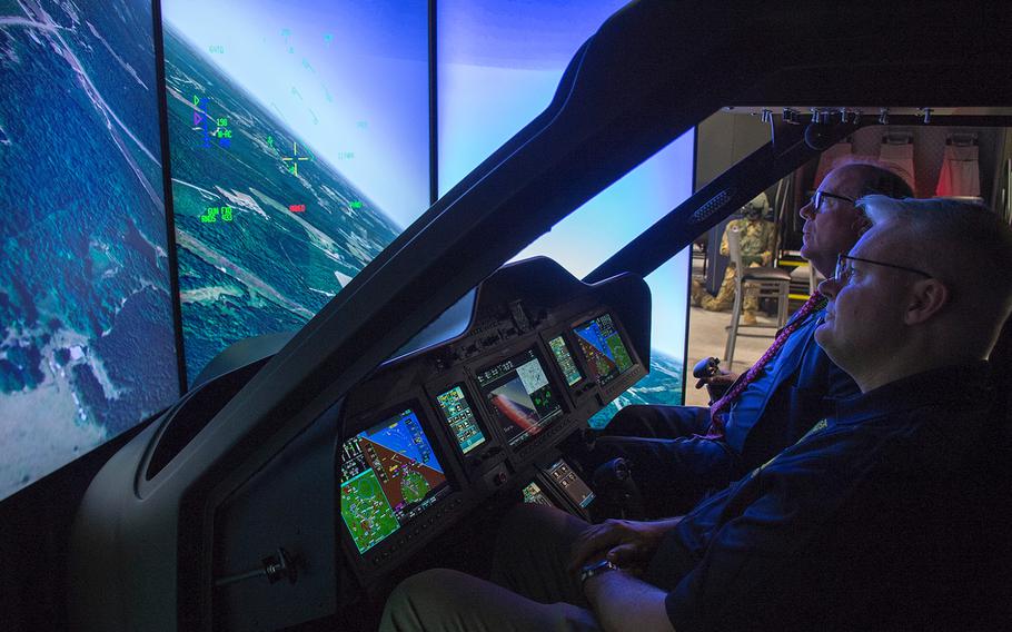 Participants sitting inside a cockpit simulator try to safely land a prototype compound helicopter during the annual AUSA convention in Washington, D.C., on Tuesday, Oct. 15, 2019. The simulated landing involved an aircraft designed by AVX Aircraft Company and L3 Harris Technologies that features dual coaxial rotors on top for vertical liftoffs and landings and two propellers in the rear for forward thrust.