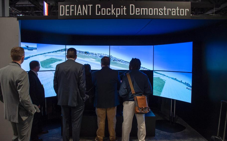 A small crowd of men gather at the annual AUSA convention in Washington, D.C., on Tuesday, Oct. 15, 2019, to watch a participant in a cockpit simulator try to safely land a Sikorsky-Boeing SB-1 Defiant compound helicopter.