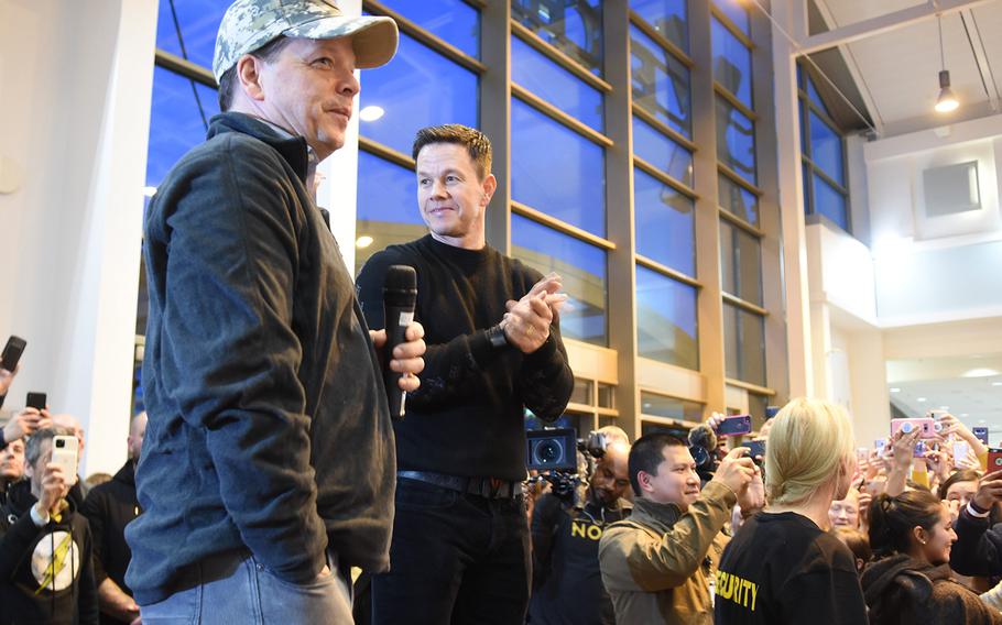 From left, Paul Wahlberg, a chef, and his brother, actor Mark Wahlberg, stand in front of a large crowd inside the food court at Ramstein Air Base, Germany, where a new Wahlburgers is scheduled to open in early January. The brothers visited the base Sunday, Dec. 15, 2019, to meet service members and their families and to talk about the restaurant.