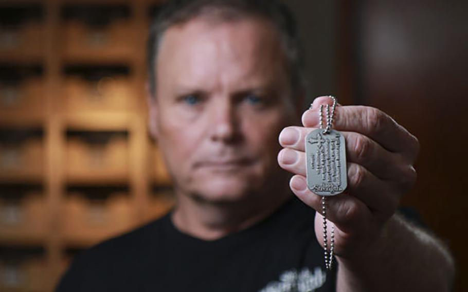 Kenny Vaughan holds a dog tag with a Bible verse sold by his company, Shields of Strength. The Marine Corps has asked the company to stop using its trademarked logo on similar products.
