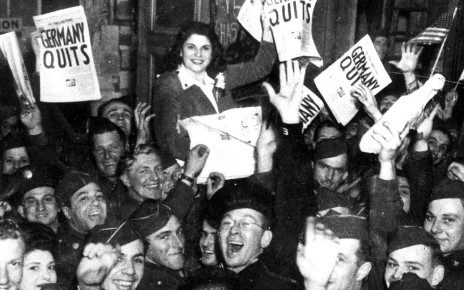 The revelers hold a copy of the May 8, 1945, London edition of The Stars and Stripes during a Victory in Europe day celebration. 

