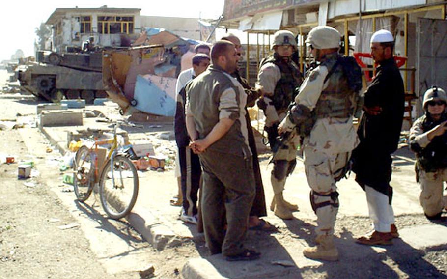 Task Force 1-7 soldiers talk with Bayji shopkeepers.