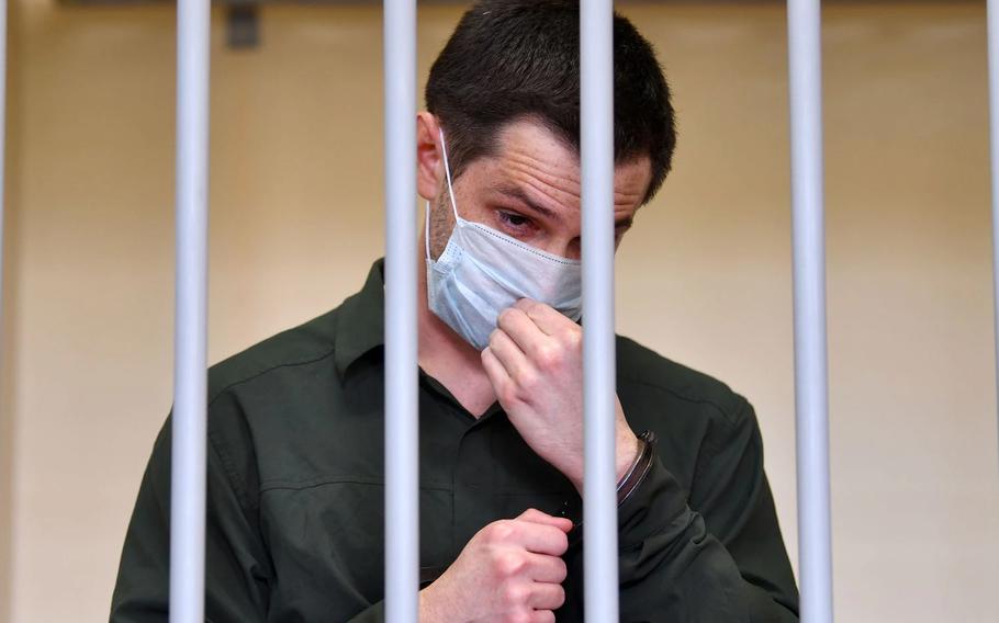 Former U.S. Marine Trevor Reed, charged with attacking police, adjusts his face mask while standing inside a defendants’ cage during his verdict hearing at Moscow’s Golovinsky district court on July 30, 2020. 