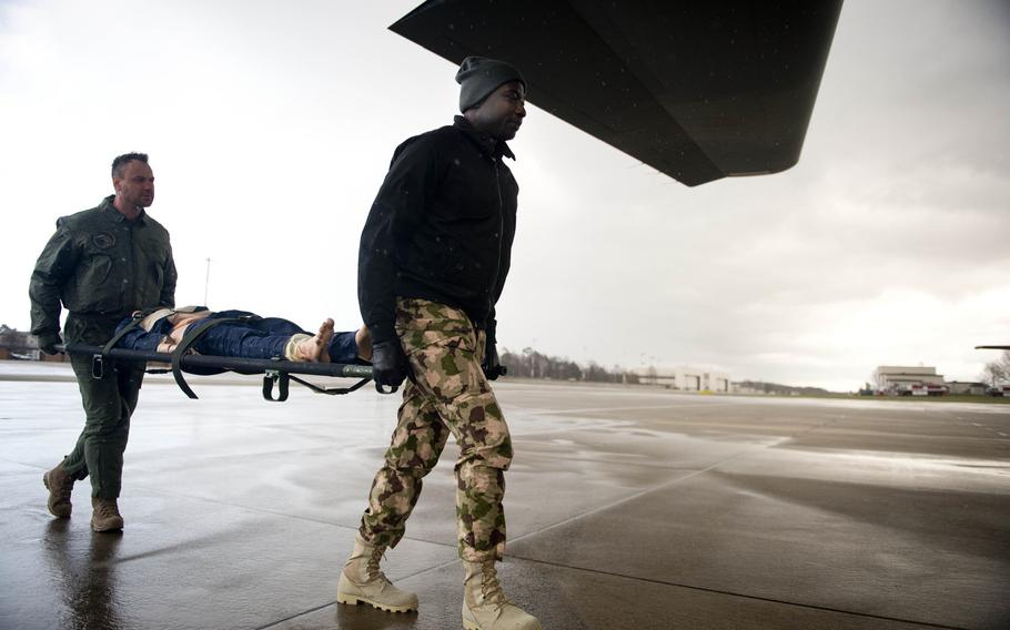 Nigerian Air Force Squadron Leader Benjamin Agom, right, and Slovenian Air Force 2nd Lt. Alvosa Lajbaher load a simulated patient onto a C-130J during aeromedical evacuation training at Ramstein Air Base, Germany, on Thursday, Jan. 18, 2018.