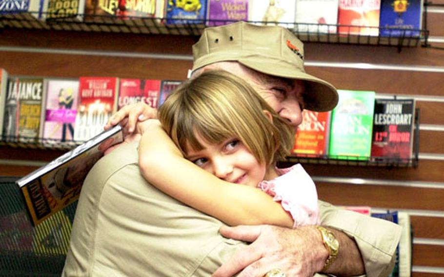Six-year-old Emma Perry is all smiles as she hugs “the Gunny,” R. Lee Ermey, at the Camp Foster Bookmark in January, 2006.