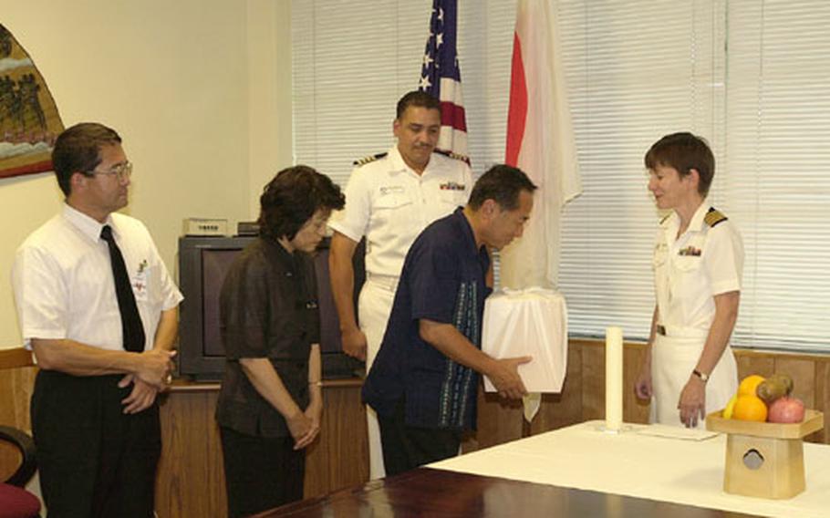 Okinawa Prefectural officials receive the wrapped box containing a skull believed to that of a Japanese soldier from Navy Capt. Patricia Buss, executive officer of the U.S. Naval Hospital on Okinawa. The skull was returned during a brief, but formal, ceremony.