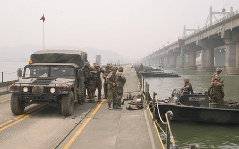Soldiers climb out of a vehicle after taking one of the first trips across a floating bridge they built over the Han River on Thursday.