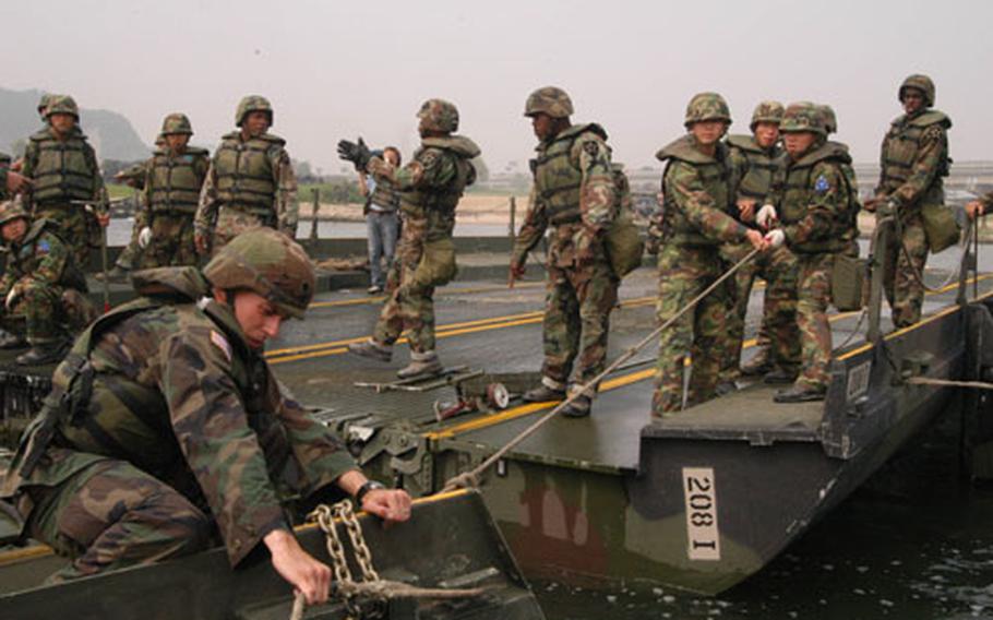 Spc. Donald Hopper,left, of the 50th Engineers Company, helps other U.S. and South Korean soldiers assemble a floating bridge raft on the Han River.