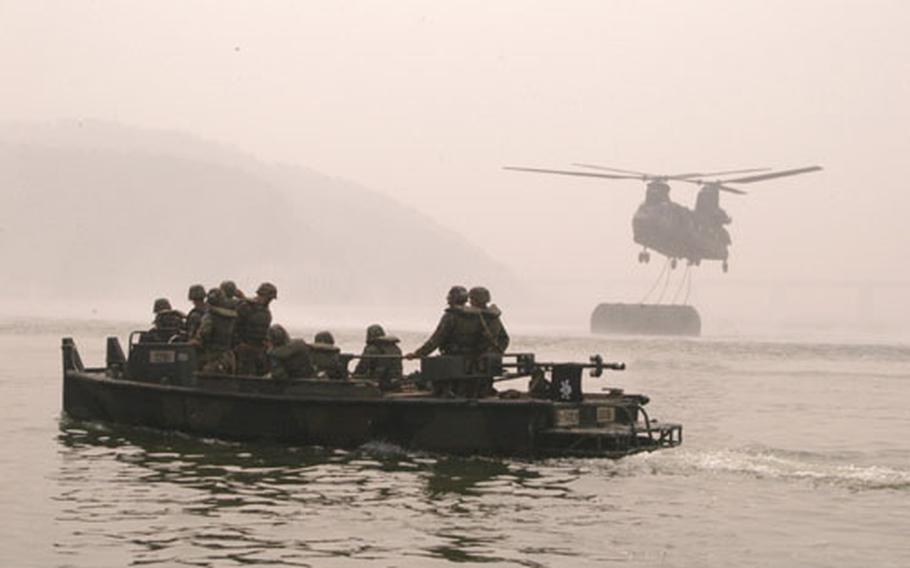 Members of the 50th Engineer Co. wait for a Chinook helicopter to release a section of a floating bridge they assembled on the Han River during training Wednesday.