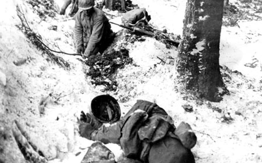 U.S. soldiers hastily dig foxholes in the snow-covered terrain as enemy artillery fire opens up near Bérisménil, Belgium, The soldier lying in the foreground had been shot.