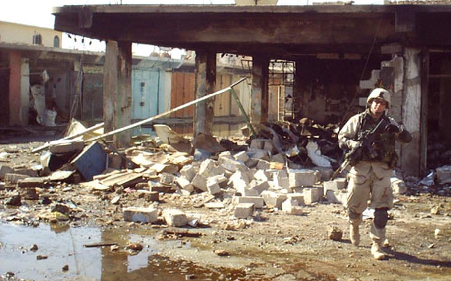 Capt. Deric Holbrook of Task Force 1-7 emerges from the rubble of a burned-out building on Bayji’s Market Street. The Iraqi city’s business district was destroyed during firefights between U.S. Army troops and local insurgents Nov. 9 and Nov. 14, 2004.