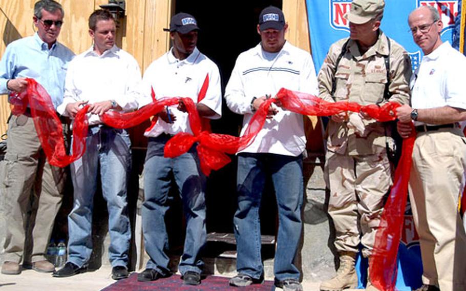 John Hanson, USO vice president of communications, Keith Coyne, Bagram USO center manager, NFL players Warrick Dunn and Larry Izzo, along with Bagram base operations commander Col. Robert Algermissen and Pete Abitante of the NFL cut the ribbon, opening the Pat Tillman USO center on Bagram Air Base, Afghanistan.