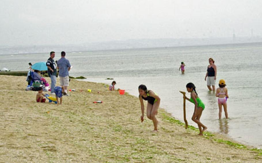 Beach visitors go about their usual activities Friday at Okinawa’s Torii Beach despite news that an 18-foot great white shark escaped from a large net off the beach’s coast earlier that morning.
