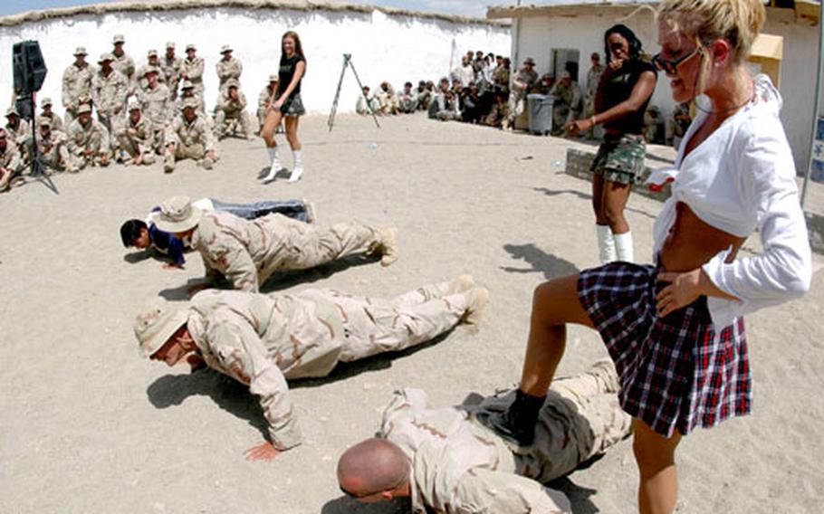 Soldiers do pushups under the watchful eye — and foot — of Denver Broncos cheerleader Holly Baack during a 4th of July show at FOB Sweeney in southeastern Afghanistan.