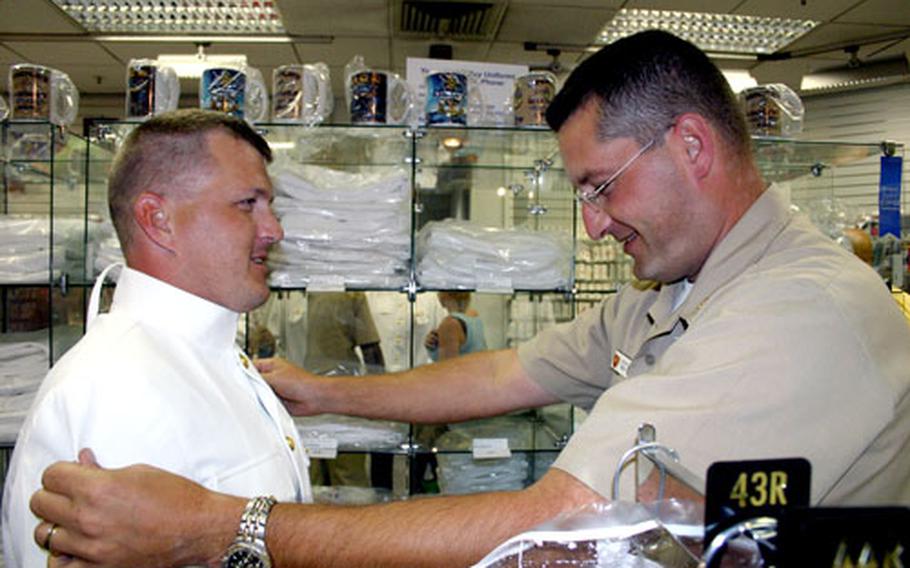Chief Petty Officer Scott Ward helps Petty Officer 1st Class Alan Dunlap pick out the correct-size in a white uniform recently at Naval Support Activity Naples, Italy. Dunlap is one of 5,282 sailors being promoted from E-6 to E-7.
