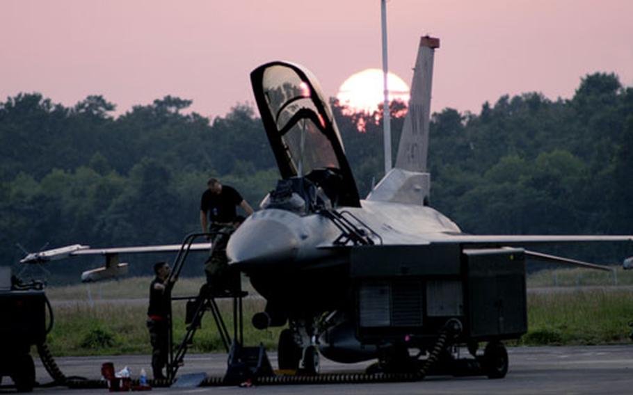 Staff Sgts. Lyle Janey and Allen Conard, along with Sr. Airman Sean Mcelree, all avionics specialists from the 35th Aircraft Maintenance Squadron, Misawa Air Base, Japan, put their finishing touches on an F-16 as the sun sets over Cope India 2006.