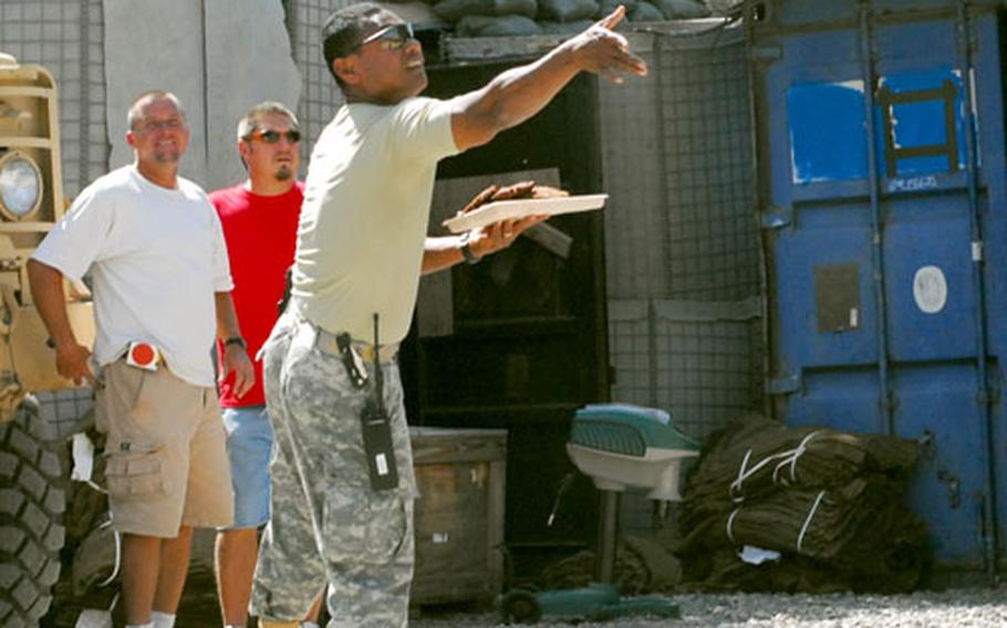 A Guam Army National Guardsman at Camp Hurso in Ethiopia tosses a hamburger patty to circling hawks.