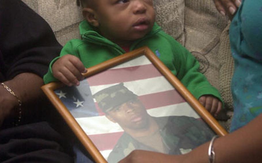 One-year-old Juwan Johnson Jr. holds a photo of his late father Sgt. Juwan Johnson. Johnson Jr. was born Dec. 1, 2005, almost five months after his father was killed in an alleged gang inititation "jumping in" ceremony in Kaiserslautern, Germany.