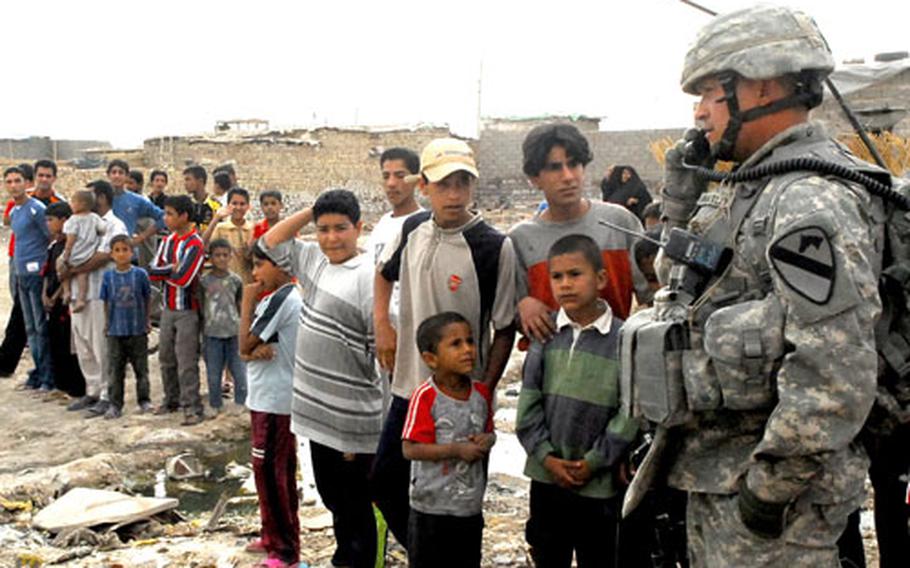 A crowd of Iraqi children forms around Sgt. 1st Class John Wheatley as he radios Company B’s command post about a stuck vehicle on patrol Monday.