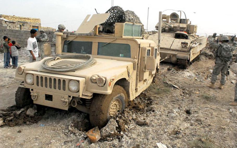 A Bradley Fighting Vehicle uses a towing cable to pull a Humvee out of a mud field on Monday in Baghdad.
